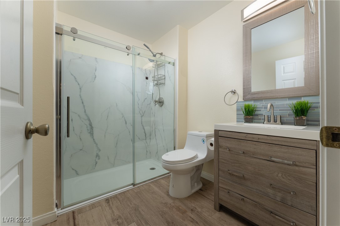 3318 North Decatur Boulevard, Unit 2143 Las Vegas, NV 89130 - Photo 11 of 34 Bathroom with a marble finish shower, light wood-type flooring, vanity, and backsplash