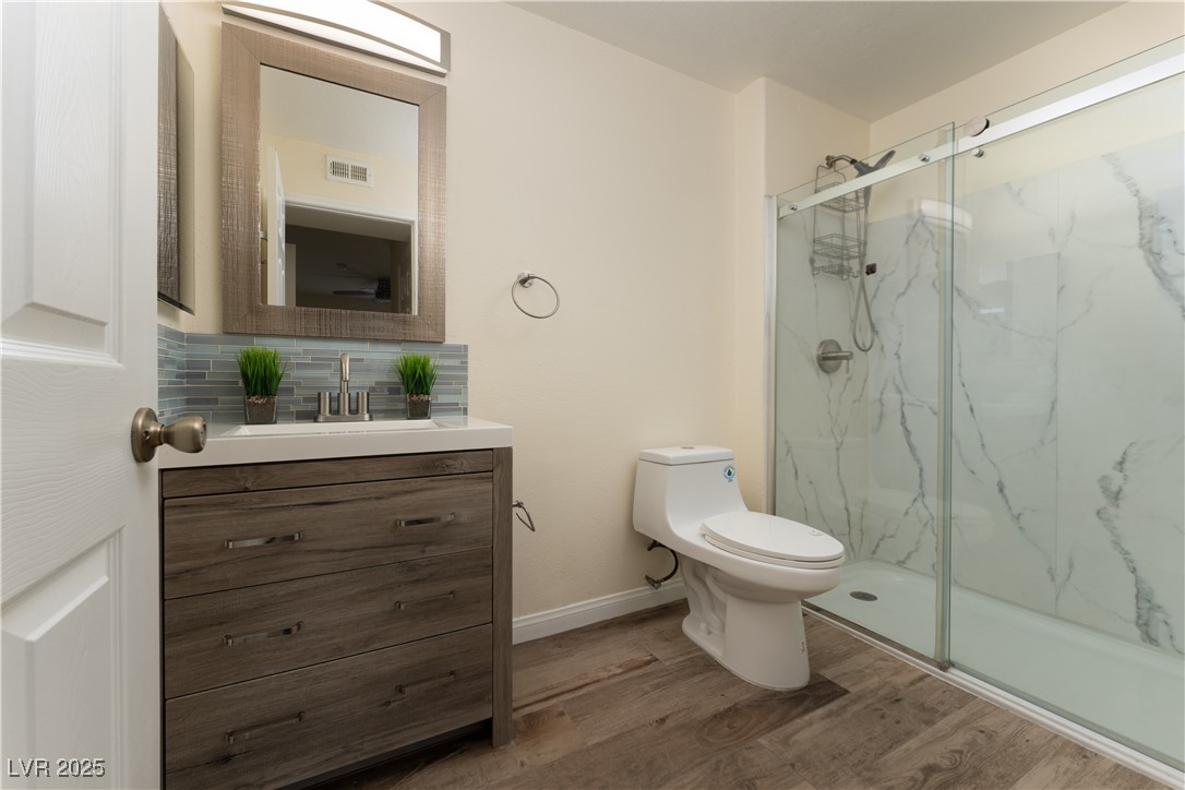 3318 North Decatur Boulevard, Unit 2143 Las Vegas, NV 89130 - Photo 15 of 34 Full bathroom featuring light wood-style floors, a marble finish shower, vanity, and tasteful backsplash