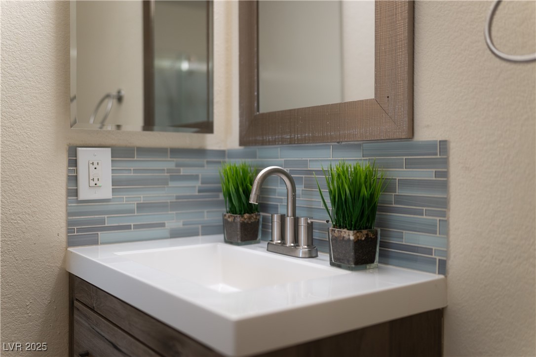 3318 North Decatur Boulevard, Unit 2143 Las Vegas, NV 89130 - Photo 17 of 34 Bathroom featuring a textured wall, decorative backsplash, and vanity