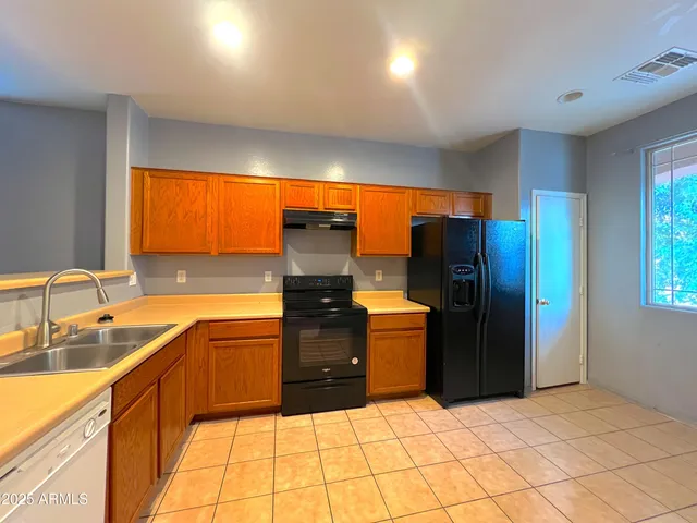 a kitchen with stainless steel appliances kitchen island granite countertop a refrigerator and a sink