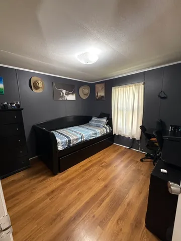 a spacious bedroom with a bed and wooden floor