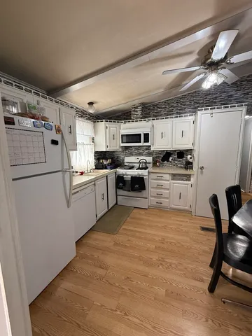 a kitchen with stainless steel appliances granite countertop a refrigerator a stove top oven a sink dishwasher and white cabinets