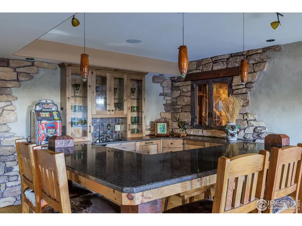 a living room with stainless steel appliances kitchen island granite countertop a table chairs and a refrigerator