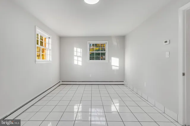 a view of an empty room with window and chandelier fan