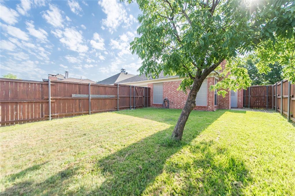 334 Touchdown Drive Irving, TX 75063 - Photo 30 of 32 Expansive backyard featuring a mature tree, red brick exterior, and full privacy fencing