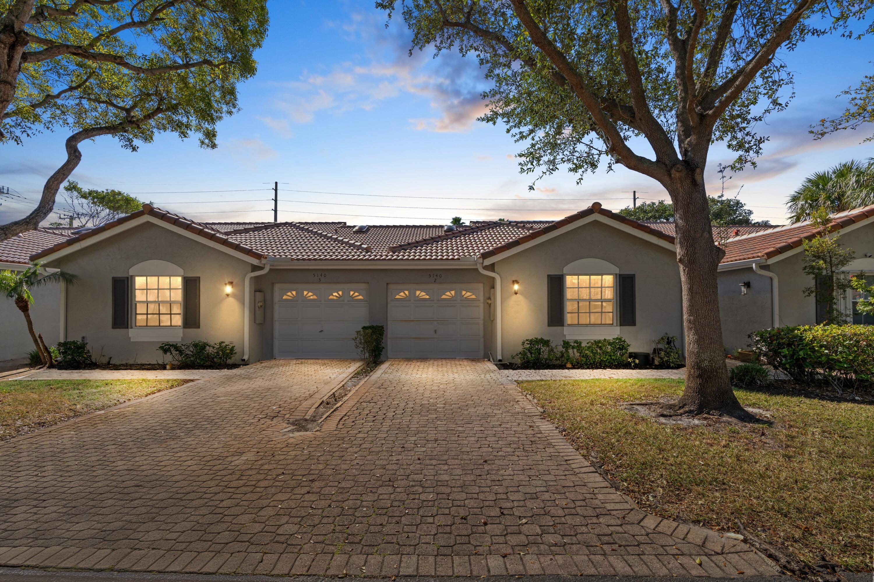 5140 Sabal Gardens Lane, Unit 2 Boca Raton, FL 33487 - Photo 2 of 34 a front view of a house with a yard and garage
