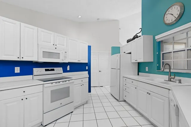 a kitchen with white cabinets and white appliances