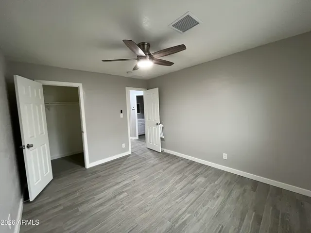 an empty room with wooden floor and ceiling fan