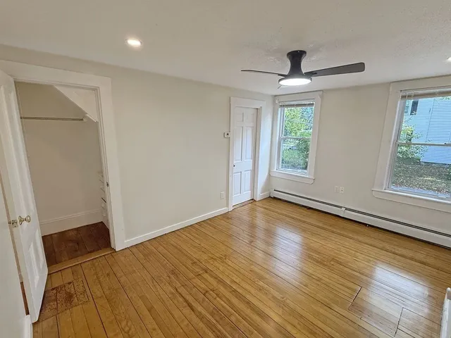 a view of empty room with wooden floor and fan