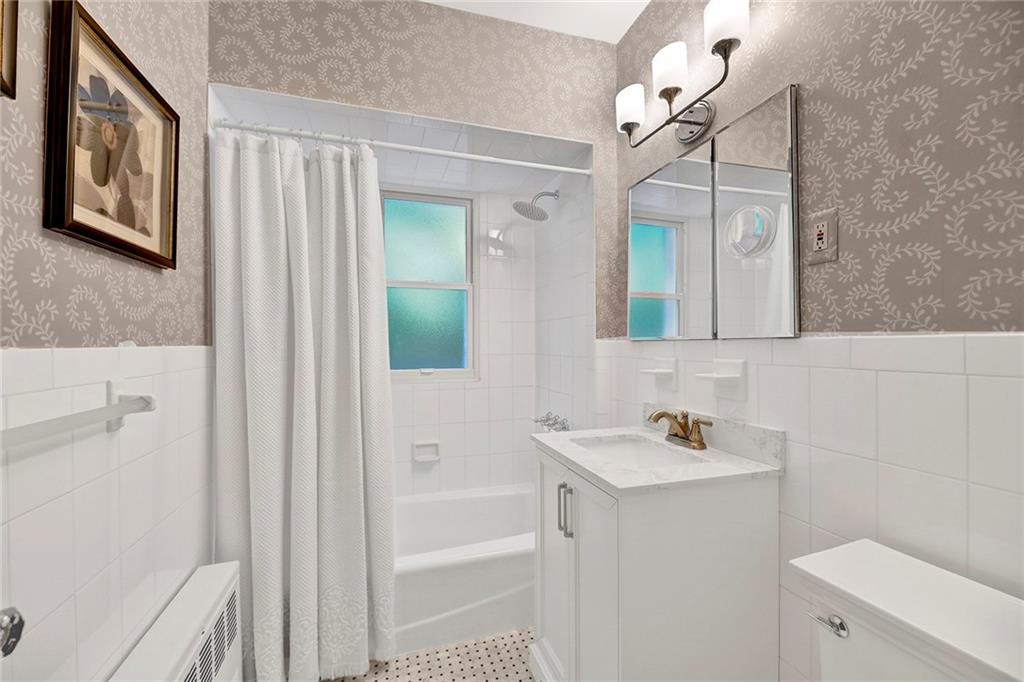 7607 Colonial Road Brooklyn, NY 11209 - Photo 22 of 35 a bathroom with a sink a toilet a mirror a vanity and shower