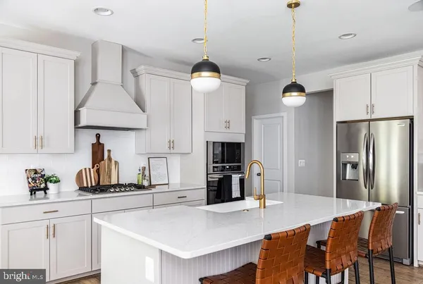 a kitchen with stainless steel appliances granite countertop a stove a refrigerator a sink a dining table and chairs with wooden floor