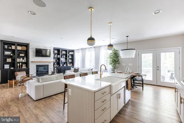 a view of a kitchen with kitchen island a stove a sink a dining table and chairs
