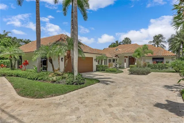 a front view of a house with a yard and potted plants