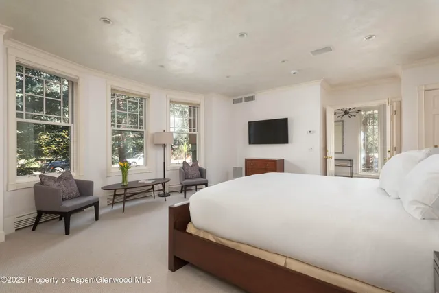 a bedroom with a bed and large windows