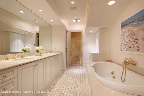 a bathroom with a double vanity sink a mirror and a bathtub
