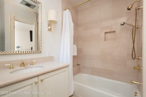 a bathroom with a granite countertop sink mirror and a bathtub