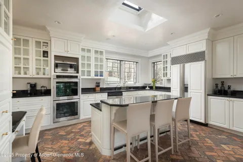 a kitchen with stainless steel appliances granite countertop a stove top oven a sink dishwasher a dining table and chairs with wooden floor