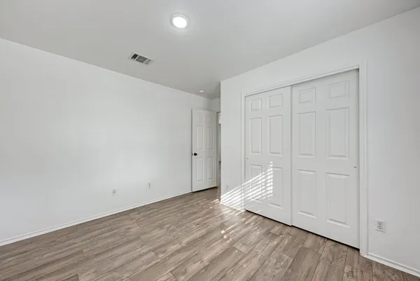 a view of an empty room with wooden floor and cabinet