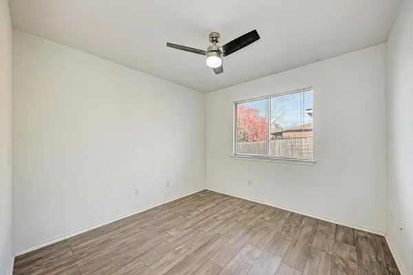 an empty room with wooden floor and ceiling fan