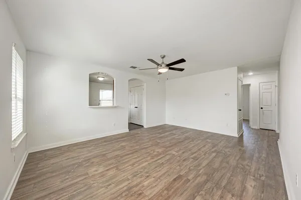 a view of empty room with wooden floor and fan