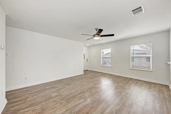 a view of empty room with wooden floor and fan