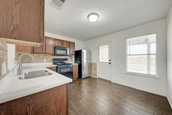 a kitchen with a sink wooden floor and stainless steel appliances
