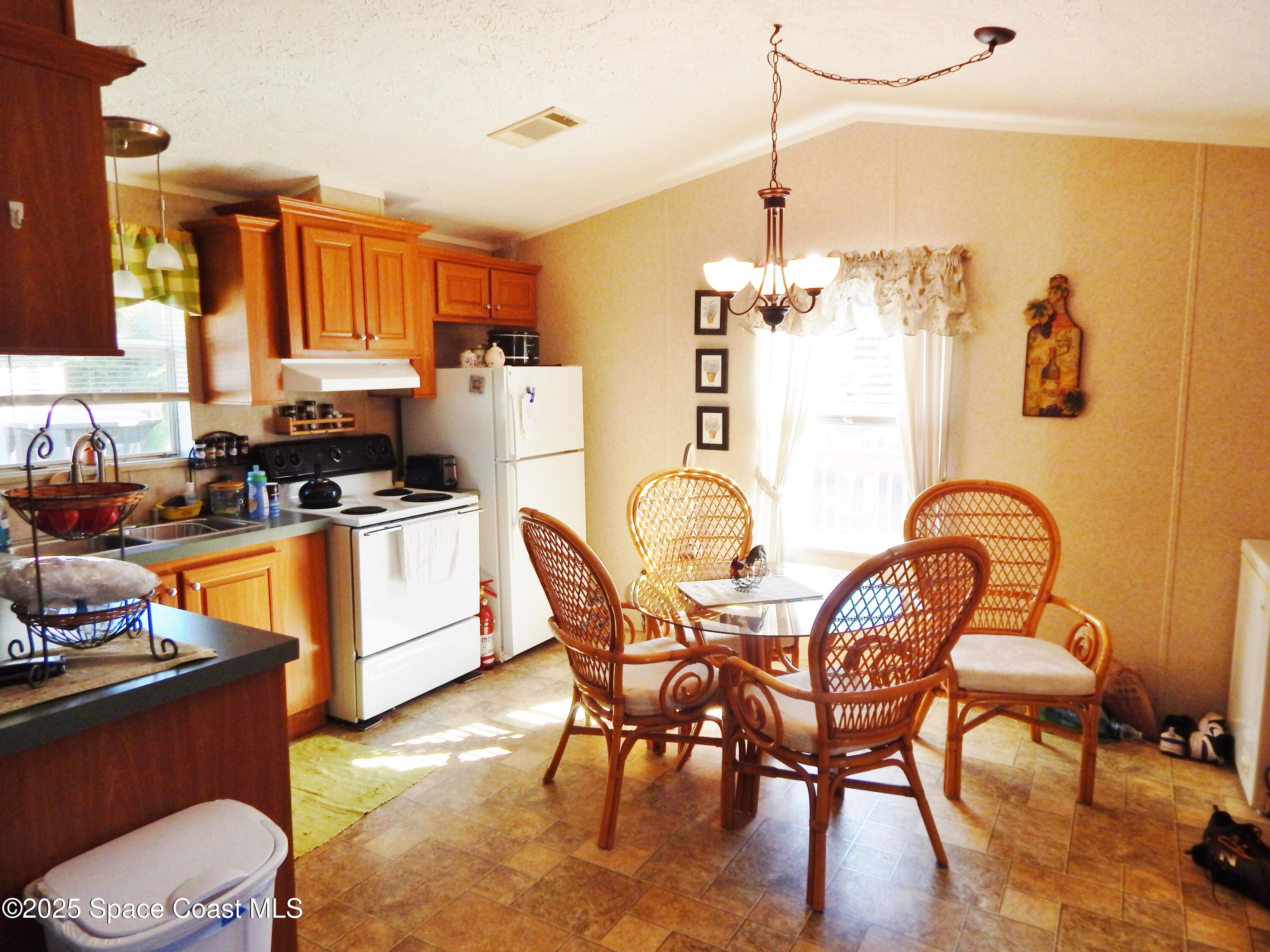 3016 Indian River Drive Northeast Palm Bay, FL 32905 - Photo 16 of 27 a kitchen with stainless steel appliances granite countertop a table and chairs