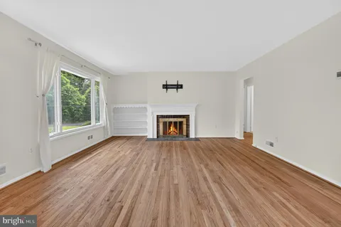 a view of empty room with wooden floor and fireplace