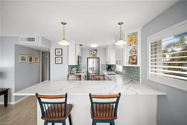 a kitchen with stainless steel appliances kitchen island granite countertop a dining table and chairs