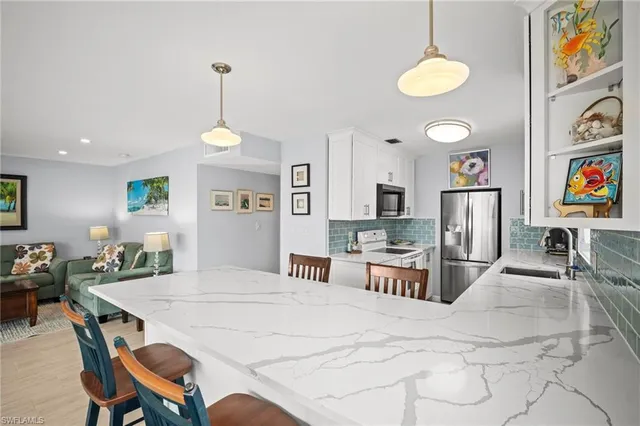 a kitchen with stainless steel appliances kitchen island granite countertop a refrigerator a stove a microwave oven a dining table and chairs with wooden floor