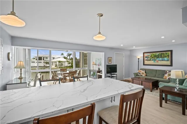 a view of a dining room and livingroom with furniture wooden floor a rug a painting and a chandelier