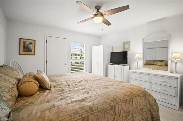 a bedroom with a bed a flat screen tv and a window