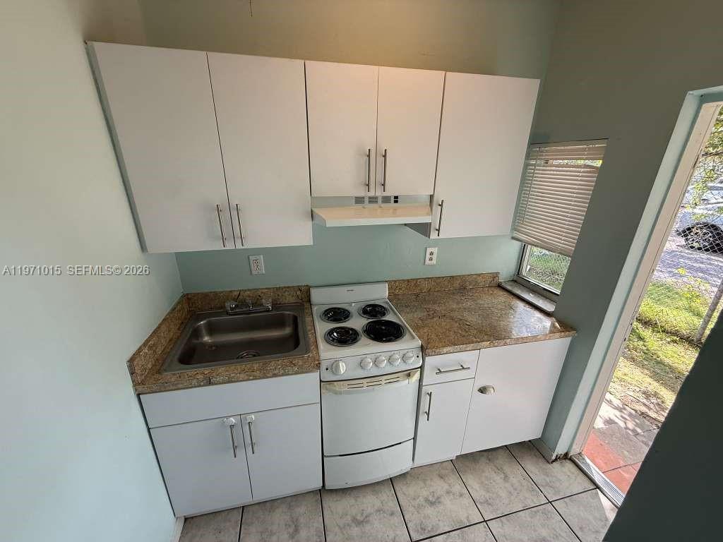 1751 Northwest 29th Street, Unit H Miami, FL 33142 - Photo 3 of 7 a kitchen with granite countertop white cabinets and white appliances