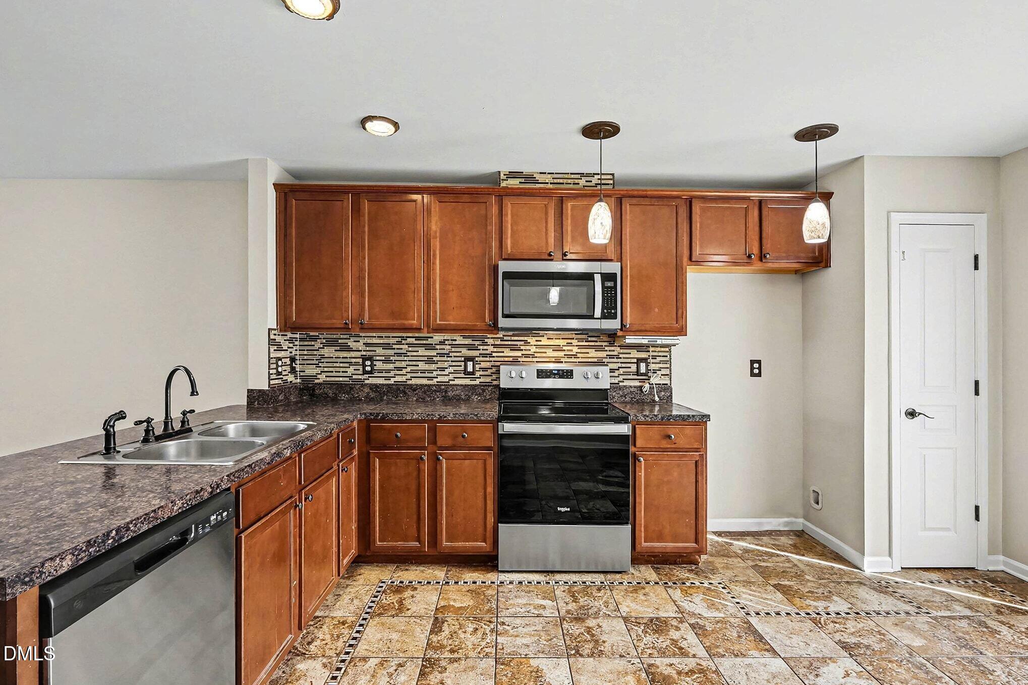 2905 Berkeley Springs Place Raleigh, NC 27616 - Photo 8 of 20 a kitchen with stainless steel appliances granite countertop a stove sink and cabinets