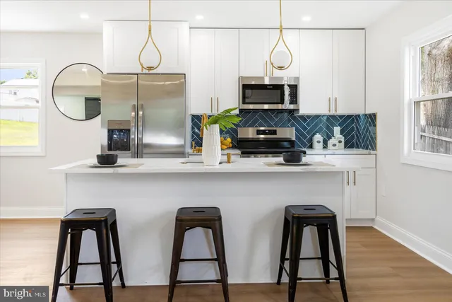 a kitchen with stainless steel appliances a microwave a stove and white cabinets