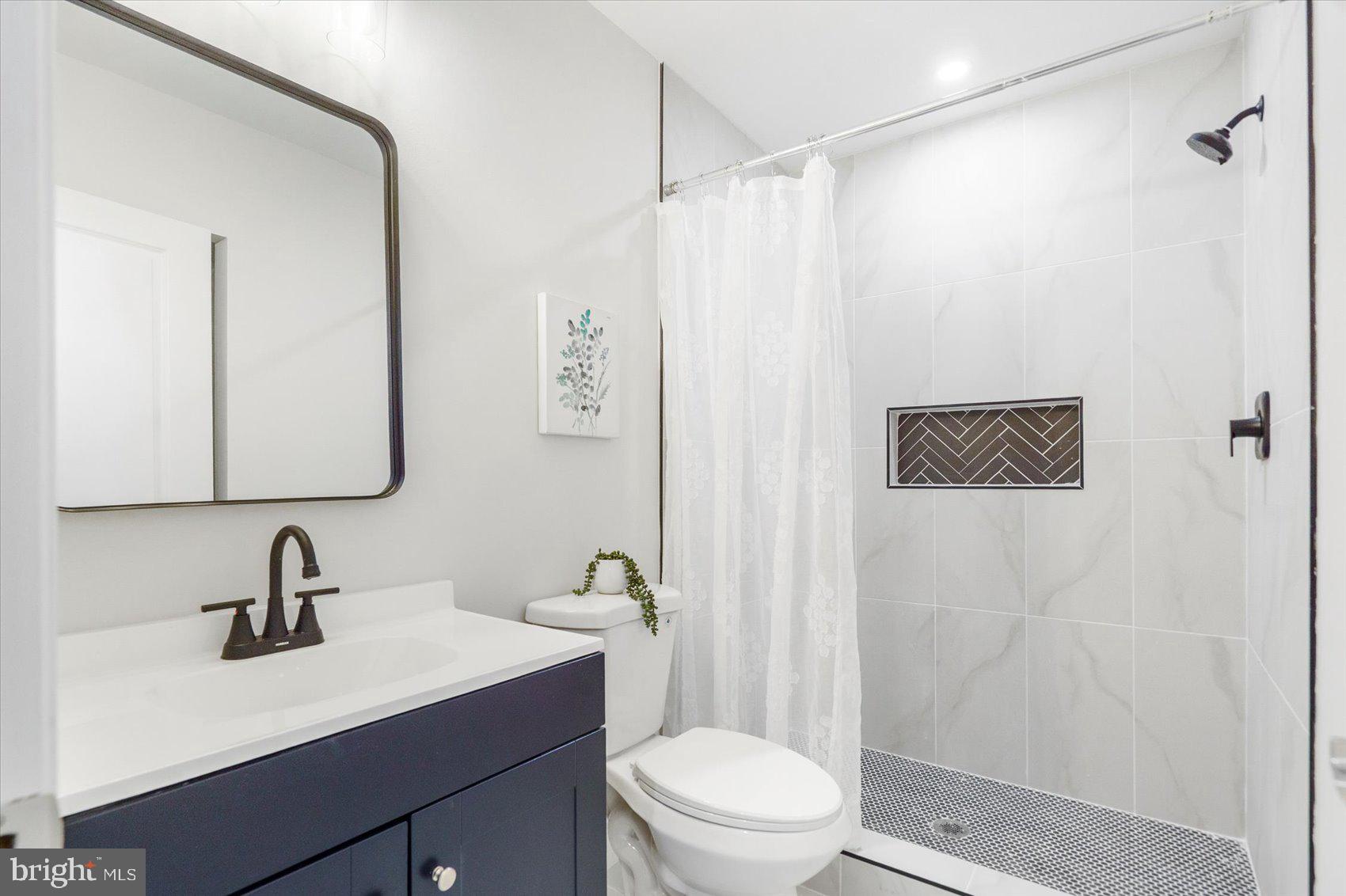 4810 Whitfield Chapel Road Lanham, MD 20706 - Photo 42 of 52 a bathroom with a sink a toilet a mirror and shower