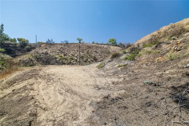 a view of a dry field with trees in the background