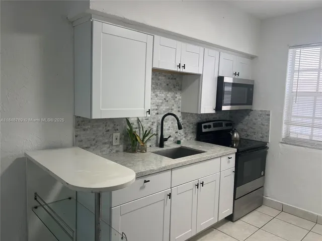 a kitchen with white cabinets a sink and appliances