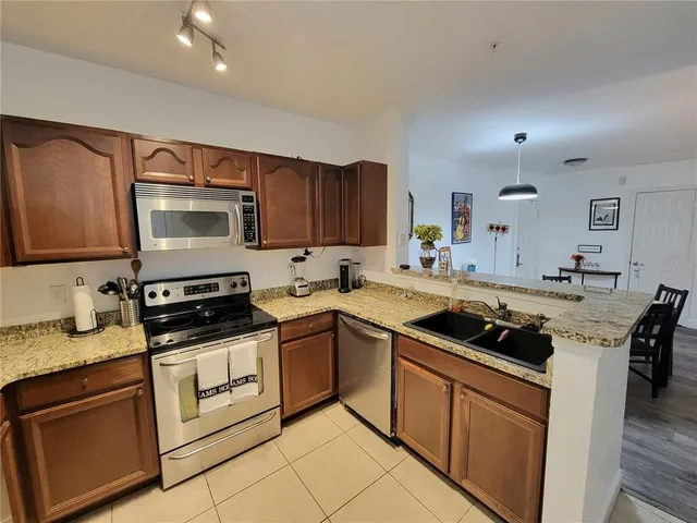 a kitchen with granite countertop stainless steel appliances a stove sink and cabinets