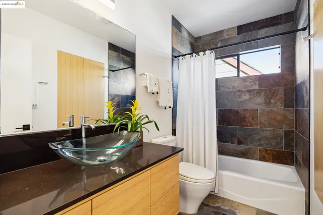 a bathroom with a granite countertop sink a toilet a mirror and shower
