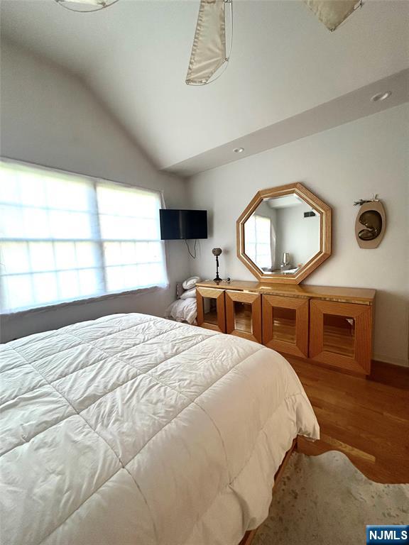 302 Grand Ridge Drive, Unit 302 Ridgefield, NJ 07657 - Photo 37 of 41 a bedroom with a bed a mirror on dresser and a window