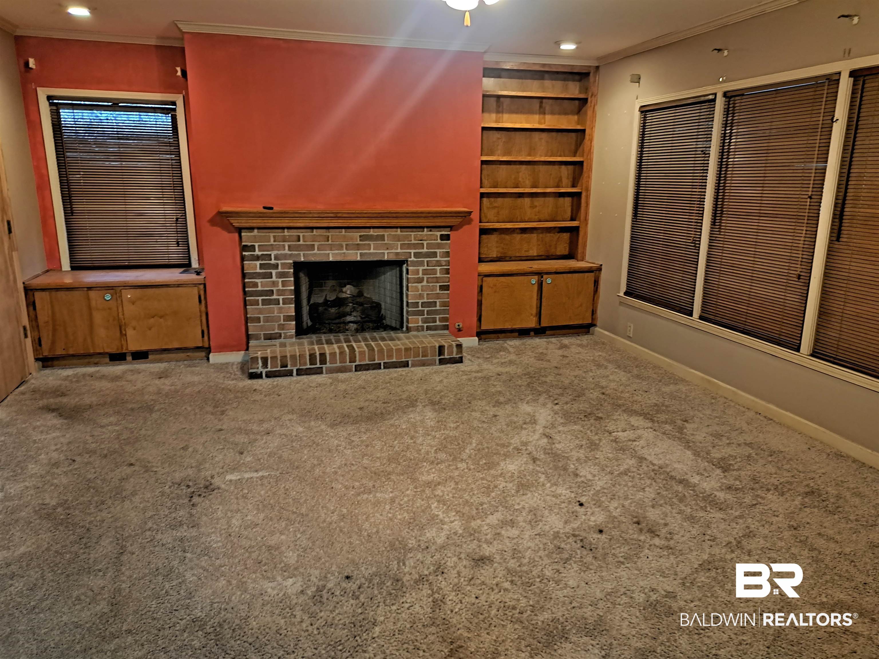 249 Newton Parkway Evergreen, AL 36401 - Photo 8 of 28 Unfurnished living room featuring crown molding, a brick fireplace, built in shelves, recessed lighting, and carpet