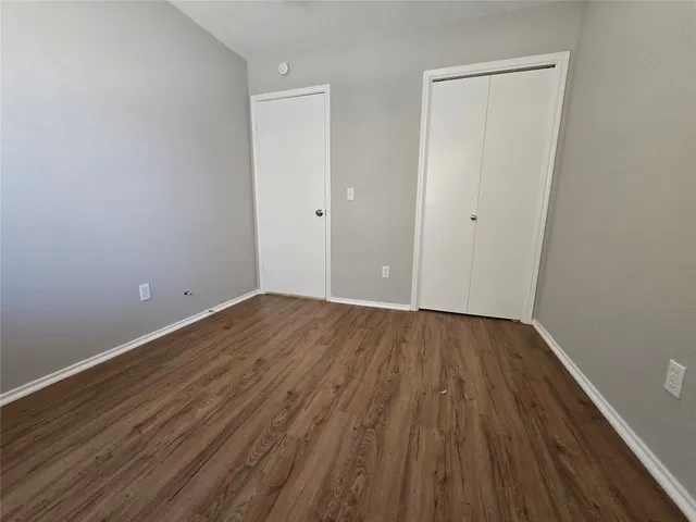 a view of an empty room with wooden floor and closet