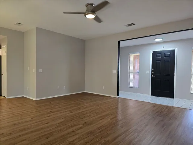 a view of an empty room with wooden floor and a window