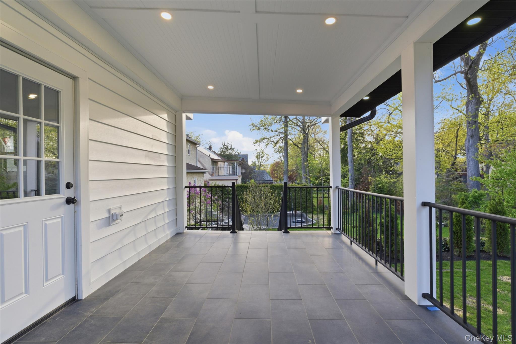 40 Calhoun Avenue New Rochelle, NY 10801 - Photo 39 of 49 Covered porch featuring dark tile flooring, white plank siding, recessed lighting, and black metal railings