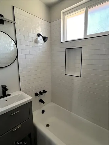 a bathroom with a bathtub sink and mirror