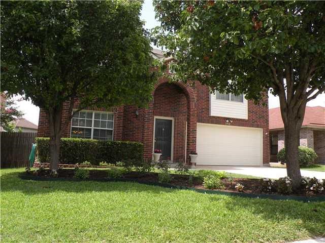 a front view of a house with a garden and trees