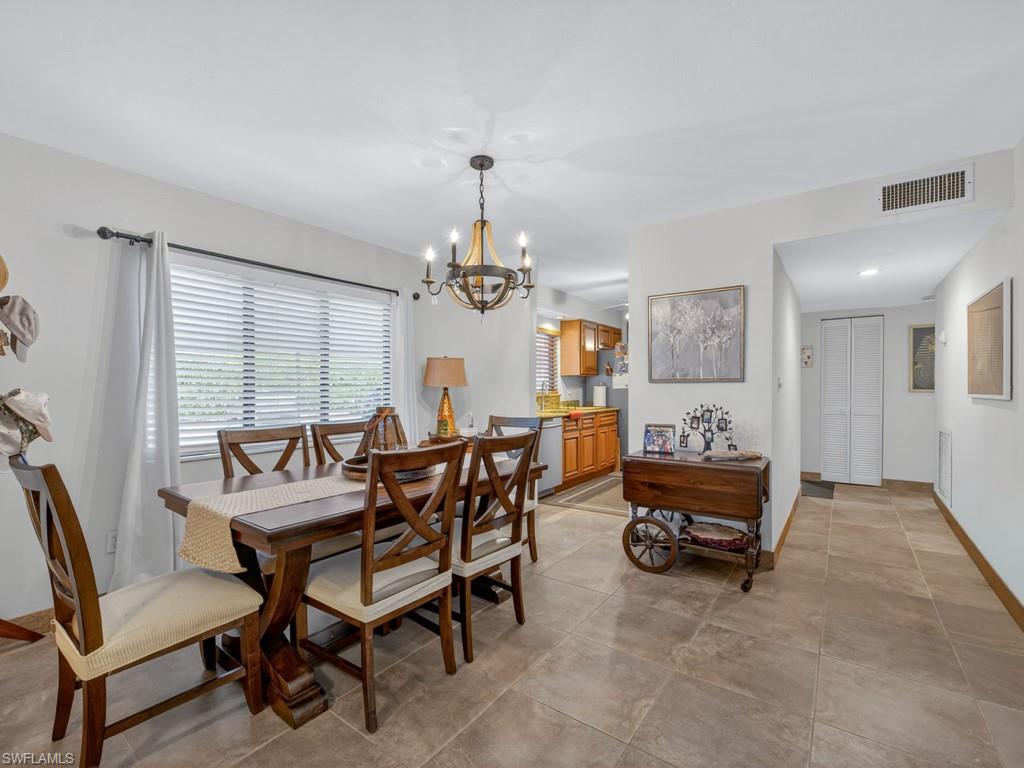 910 Vanderbilt Beach Road, Unit 317W Naples, FL 34108 - Photo 4 of 14 a dining room with furniture and a chandelier