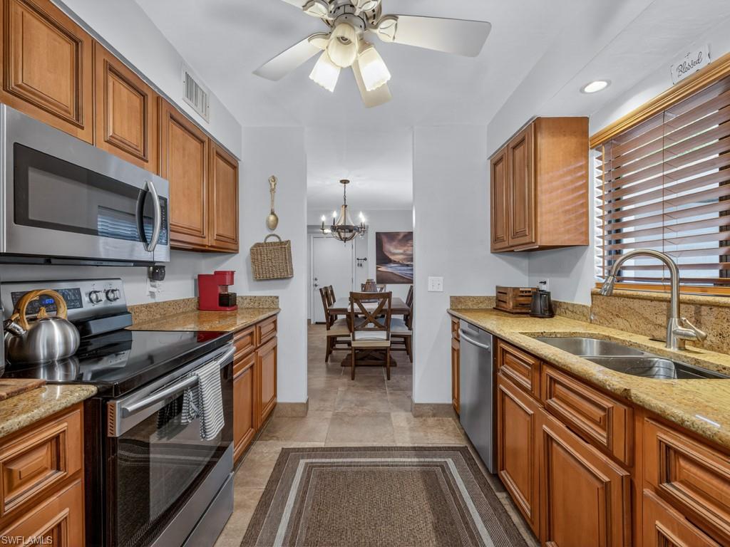 910 Vanderbilt Beach Road, Unit 317W Naples, FL 34108 - Photo 5 of 14 a kitchen with a stove a sink and cabinets