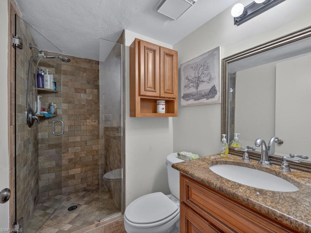 910 Vanderbilt Beach Road, Unit 317W Naples, FL 34108 - Photo 8 of 14 a bathroom with a granite countertop sink toilet a mirror and shower